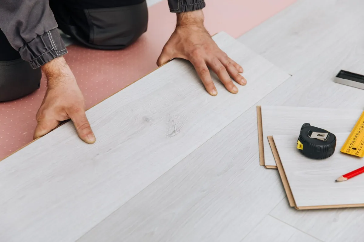 Instalador ensamblando piso vinílico en tableta tipo click sobre base preparada